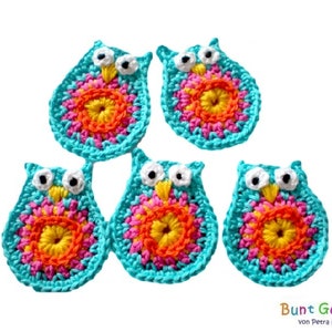 Pode incluir: Cinco enfeites de coruja de crochê em azul turquesa com detalhes em rosa, laranja e amarelo. As corujas têm olhos e bicos brancos.