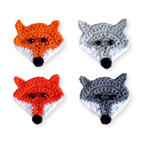 Könnte beinhalten: Vier gehäkelte Tierkopf-Applikationen. Zwei sind orange Füchse mit weißen Akzenten und zwei sind graue Wölfe mit weißen Akzenten.