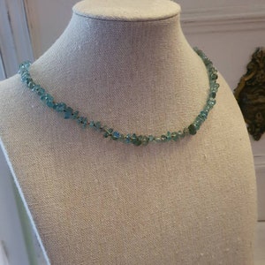 May include: A delicate necklace made with light blue gemstone chips strung on a gold wire.
