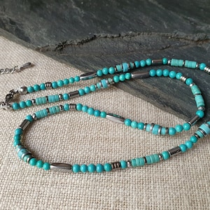 Peut inclure: Un collier de perles turquoise et argent avec une fermeture à fermoir. Le collier est composé de perles rondes turquoise et de perles d'espacement argentées.