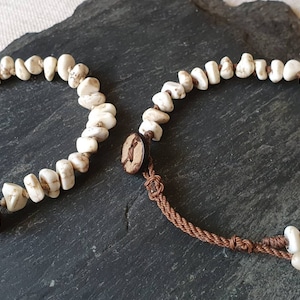 May include: Two white and brown stone beaded bracelets with brown cord and wooden button closures.