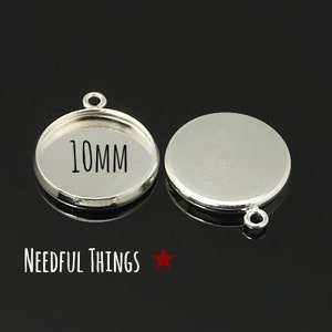 Pode incluir: Duas bandejas de pendente de metal prateadas com um laço na parte superior. A bandeja à esquerda tem um diâmetro de 10 mm e está etiquetada como "10MM".