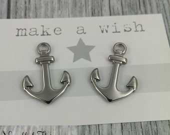 May include: Two silver anchor charms with the text "make a wish" and "Needful Things" on a white card.