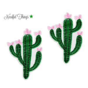 Könnte beinhalten: Zwei grüne Kaktus-Patches mit rosa Blüten. Die Kaktus-Patches sind gestickt und haben einen weißen Hintergrund.