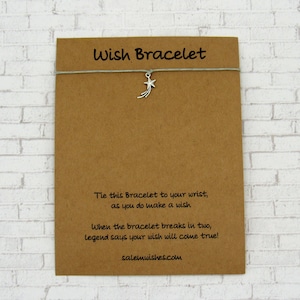 May include: A brown card with the text "Wish Bracelet" printed on it. The card has a silver star charm attached to a gray string. The text on the card reads: "Tie this Bracelet to your wrist, as you do make a wish. When the bracelet breaks in two, legend says your wish will come true! salemwishes.com"