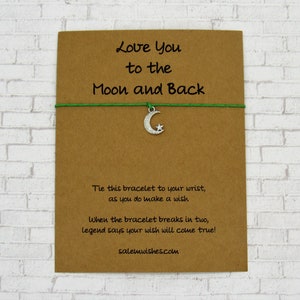 May include: A brown card with the text "Love You to the Moon and Back" and a green string bracelet with a silver crescent moon charm. The card also includes instructions for making a wish with the bracelet.
