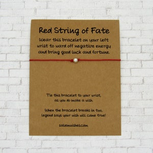 May include: Red string bracelet with a silver bead. The card reads "Red String of Fate. Wear this bracelet on your left wrist to ward off negative energy and bring good luck and fortune. Tie this bracelet to your wrist, as you do make a wish. When the bracelet breaks in two, legend says your wish will come true! salemwishes.com"