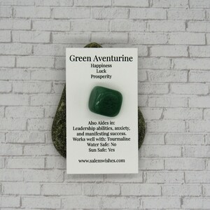 May include: Green aventurine crystal with a card that says "Green Aventurine, Happiness, Luck, Prosperity, Also Aides in: Leadership abilities, anxiety, and manifesting success. Works well with: Tourmaline, Water Safe: No, Sun Safe: Yes, www.salemwishes.com"