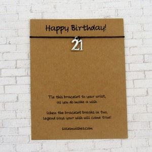 May include: A brown card with the text "Happy Birthday!" and a silver charm with the number "21" on a black string. The card also includes text about making a wish. The website salemwishes.com is at the bottom.