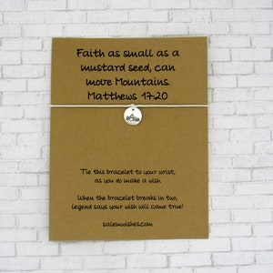 May include: A brown card with the text "Faith as small as a mustard seed, can move Mountains. Matthews 17:20" and a white string tied around it with a silver charm of a mountain. The card also says "Tie this bracelet to your wrist, as you do make a wish. When the bracelet breaks in two, legend says your wish will come true! salemwishes.com".