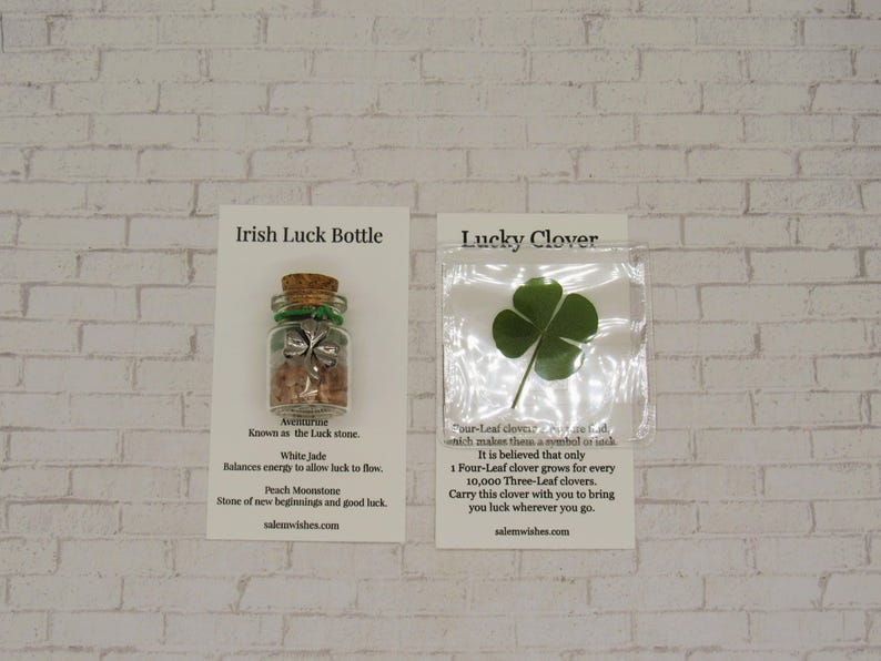 May include: Two cards with a green four-leaf clover and a small glass bottle filled with crystals and a silver clover charm. The cards have text that reads "Irish Luck Bottle" and "Lucky Clover".