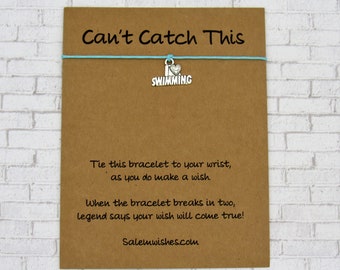 May include: A brown card with the text "Can't Catch This" and a charm that says "I love swimming" on a blue string. The card also includes the text "Tie this bracelet to your wrist, as you do make a wish. When the bracelet breaks in two, legend says your wish will come true! Salemwishes.com"
