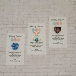 May include: Three white cards with the text "Happy Easter!" and a small heart-shaped charm. The text on the cards reads "Here is a little pocket hug for you to remember that some bunny loves you! Love, The Easter Bunny."