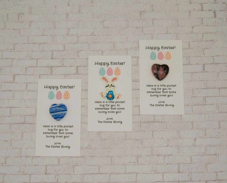 May include: Three white cards with the text "Happy Easter!" and a small heart-shaped charm. The text on the cards reads "Here is a little pocket hug for you to remember that some bunny loves you! Love, The Easter Bunny."