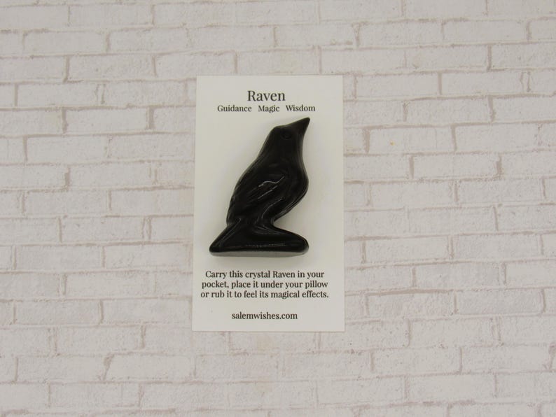 Pode incluir: Uma estatueta de corvo preto em um cart&atilde;o branco com o texto "Raven, Guidance Magic Wisdom." O cart&atilde;o tamb&eacute;m inclui instru&ccedil;&otilde;es e o site salemwishes.com. O corvo &eacute; uma escultura escura e brilhante.
