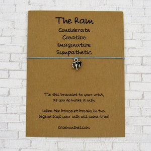 May include: A brown card with the text "The Ram" and a list of personality traits: Considerate, Creative, Imaginative, Sympathetic. A blue string bracelet with a silver ram charm is attached to the card. The text "Tie this bracelet to your wrist, as you do make a wish. When the bracelet breaks in two, legend says your wish will come true! salemwishes.com" is printed on the card.