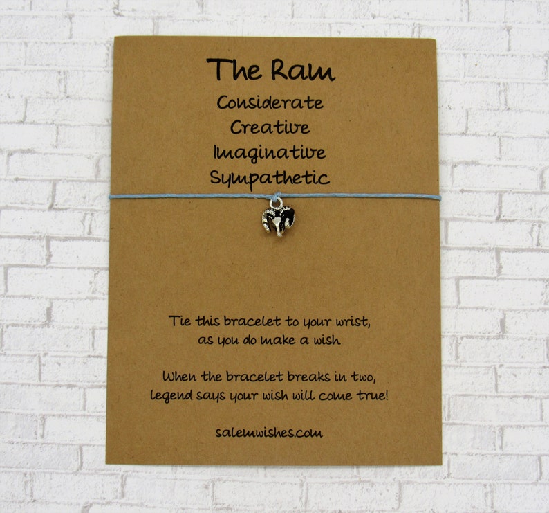 May include: A brown card with the text "The Ram" and a list of personality traits: Considerate, Creative, Imaginative, Sympathetic. A blue string bracelet with a silver ram charm is attached to the card. The text "Tie this bracelet to your wrist, as you do make a wish. When the bracelet breaks in two, legend says your wish will come true! salemwishes.com" is printed on the card.