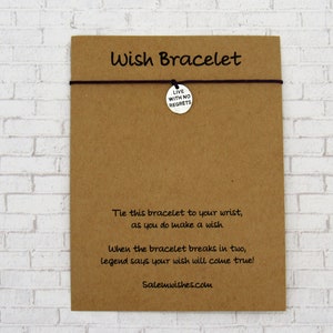 K&ouml;nnte beinhalten: Eine braune Karte mit dem Text "Wish Bracelet" darauf gedruckt. Die Karte hat eine schwarze Schnur mit einem silbernen Anh&auml;nger, auf dem "Live with no regrets" steht. Die Karte enth&auml;lt auch Anweisungen zur Verwendung des Armbands.