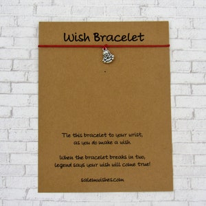 May include: Red string wish bracelet with a silver charm of a Santa Claus. The card reads "Wish Bracelet" and includes instructions on how to make a wish and the legend that says your wish will come true when the bracelet breaks in two. The card also includes the website salemwishes.com.