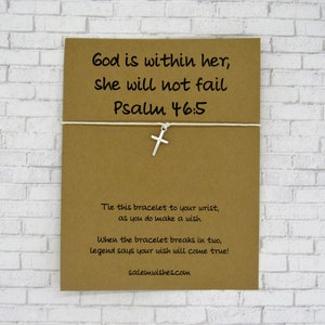 May include: A brown card with the text "God is within her, she will not fail Psalm 46:5" and a silver cross charm attached to a white string bracelet. The card also includes instructions for making a wish with the bracelet.