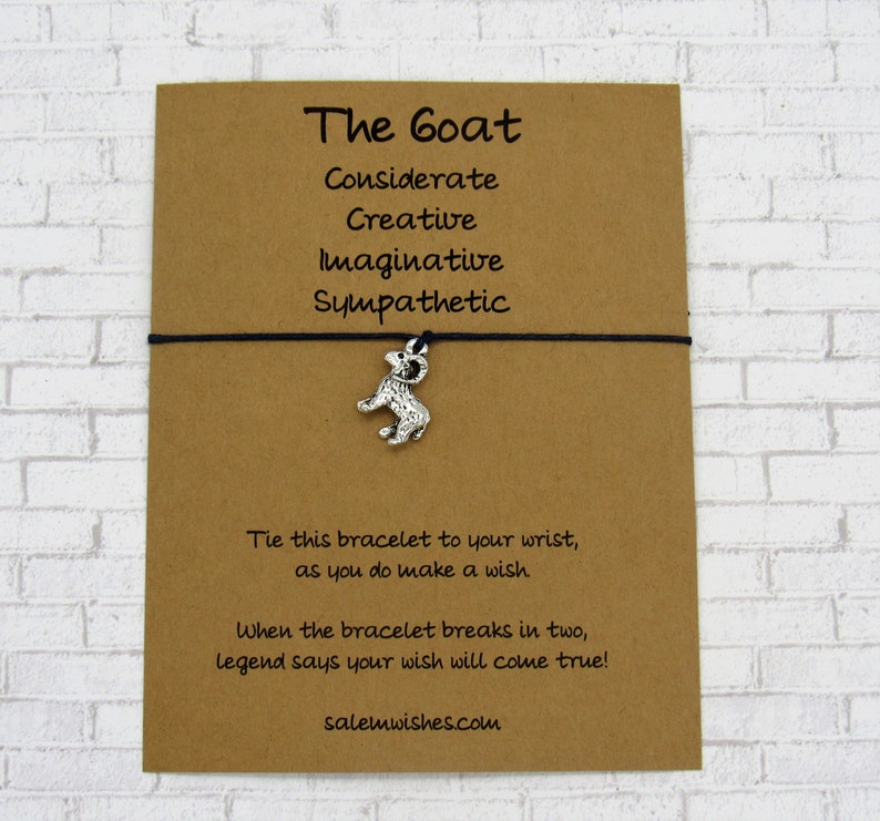 May include: A brown card with black string and a silver goat charm. The card reads "The Goat" and lists the following traits: "Considerate, Creative, Imaginative, Sympathetic". The card also says "Tie this bracelet to your wrist, as you do make a wish. When the bracelet breaks in two, legend says your wish will come true!" and "salemwishes.com".