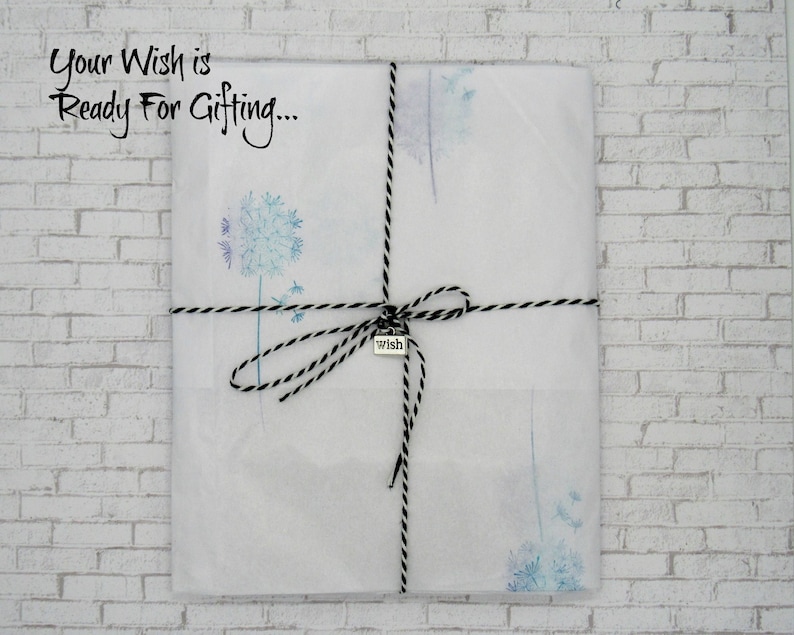 May include: A white gift bag with a black and white twine bow and a silver charm that says "wish". The bag is decorated with a watercolor design of dandelion seeds. The text "Your Wish is Ready For Gifting..." is printed on the bag.