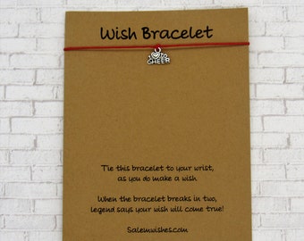 Peut inclure: Un bracelet en cordon rouge avec un charme argenté qui dit "J'aime encourager". Le bracelet est livré avec une carte qui dit "Attachez ce bracelet à votre poignet, en faisant un vœu. Lorsque le bracelet se brise en deux, la légende dit que votre vœu se réalisera ! Salemwishes.com"