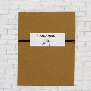 May include: A brown paper envelope with a white tag tied to it with black string. The tag has a dandelion illustration and the text "Make A Wish".