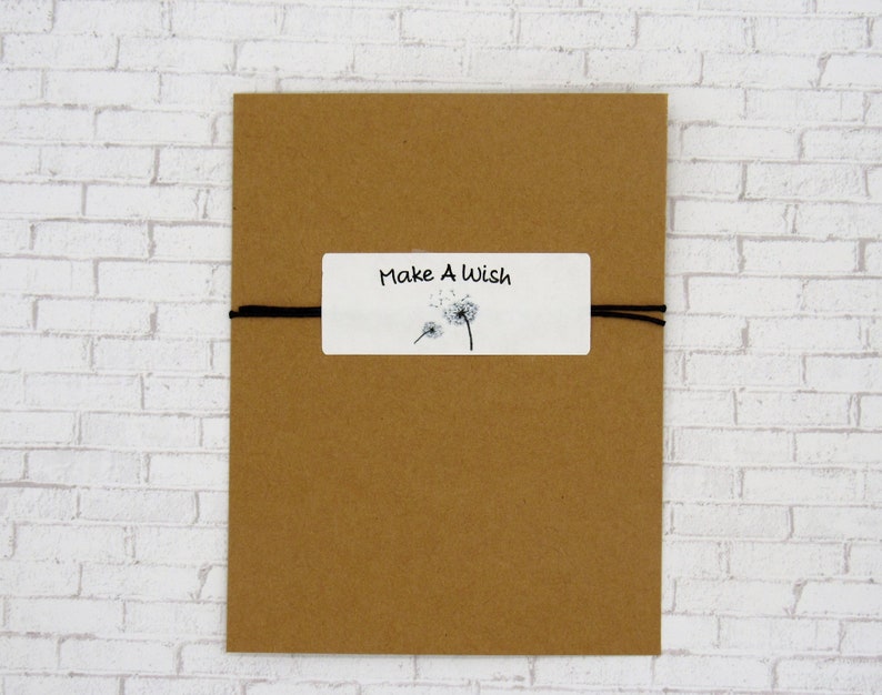 May include: A brown paper envelope with a white tag tied to it with black string. The tag has a dandelion illustration and the text "Make A Wish".