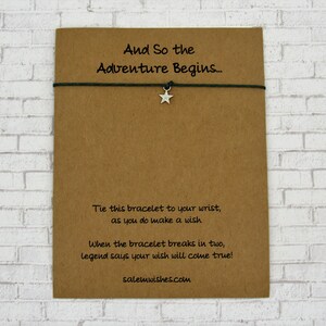 K&ouml;nnte beinhalten: Eine braune Karte mit dem Text "And So the Adventure Begins..." und Anweisungen, das Armband an Ihrem Handgelenk zu binden und einen Wunsch zu machen. Das Armband ist gr&uuml;n mit einem silbernen Sternanh&auml;nger. Die Karte sagt auch "When the bracelet breaks in two, legend says your wish will come true!" und enth&auml;lt die Website salemwishes.com.
