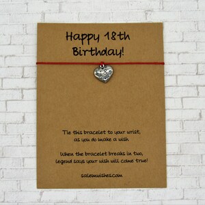 May include: A brown card with the text "Happy 18th Birthday!" and a red string bracelet. The bracelet has a silver heart charm with the number 18. Additional text on the card explains the bracelet's wish-granting legend.