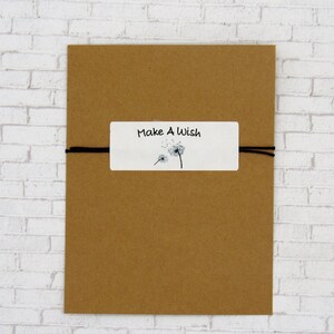 May include: A brown paper envelope with a white tag tied to it with black string. The tag has a dandelion illustration and the text "Make A Wish".