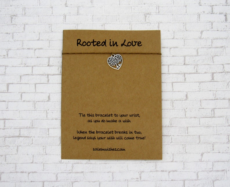 May include: A brown card with the text "Rooted in Love" and instructions for a wish bracelet. The bracelet has a silver charm shaped like a tree inside a heart.