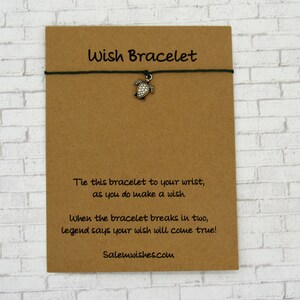 May include: A brown card with the text "Wish Bracelet" printed on it. The card has a black string with a silver turtle charm attached to it. The text on the card reads: "Tie this bracelet to your wrist, as you do make a wish. When the bracelet breaks in two, legend says your wish will come true! Salemwishes.com"