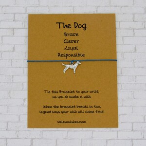 May include: A brown card with the text "The Dog" and the words "Brave, Clever, Loyal, Responsible" printed on it. A blue string bracelet with a silver dog charm is attached to the card. The card also includes the text "Tie this Bracelet to your wrist, as you do make a wish. When the bracelet breaks in two, legend says your wish will come true! salemwishes.com"