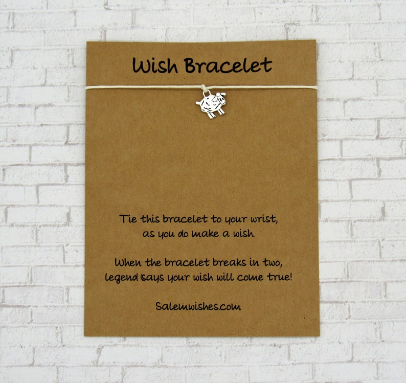 May include: A brown card with white string and a silver charm of a sheep. The card reads "Wish Bracelet" and includes instructions to tie the bracelet to your wrist and make a wish. The card also says that when the bracelet breaks in two, legend says your wish will come true. The card is signed "Salemwishes.com".