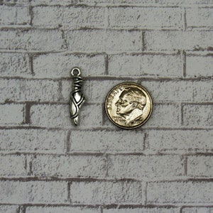 May include: Silver charm in the shape of a ballet slipper, next to a US dime for size comparison.