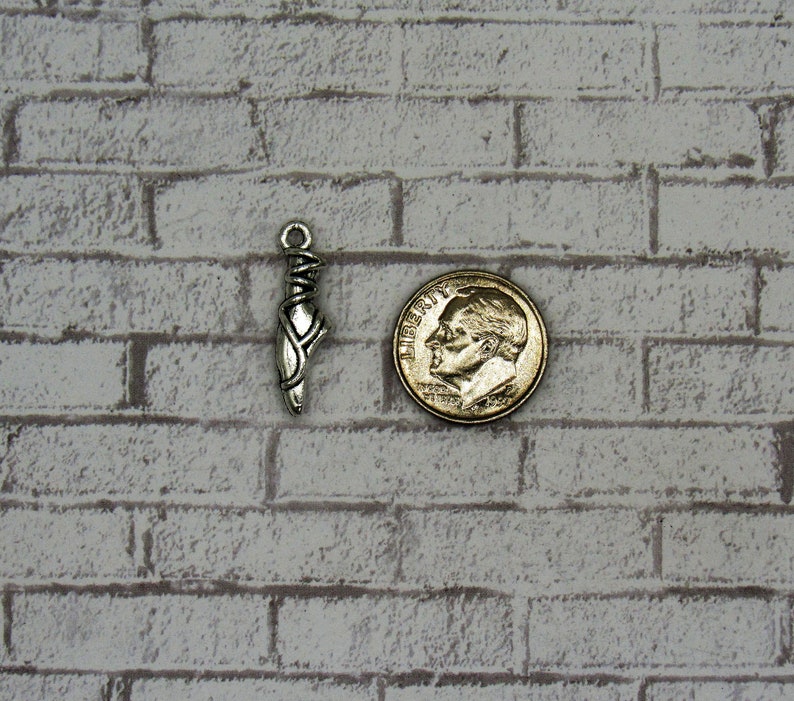May include: Silver charm in the shape of a ballet slipper, next to a US dime for size comparison.