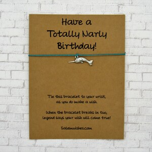 May include: A brown card with the text "Have a Totally Narly Birthday!" and a turquoise string bracelet with a silver narwhal charm. The card also includes the text "Tie this bracelet to your wrist, as you do make a wish. When the bracelet breaks in two, legend says your wish will come true! Salemwishes.com".