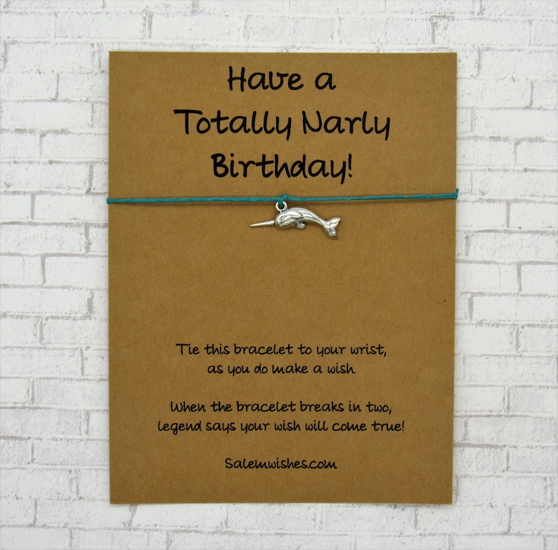May include: A brown card with the text "Have a Totally Narly Birthday!" and a turquoise string bracelet with a silver narwhal charm. The card also includes the text "Tie this bracelet to your wrist, as you do make a wish. When the bracelet breaks in two, legend says your wish will come true! Salemwishes.com".