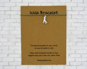 May include: A brown card with the text "Wish Bracelet" printed in green. The card has a silver charm of a roller skate attached to a teal string. The text on the card reads: "Tie this bracelet to your wrist, as you do make a wish. When the bracelet breaks in two, legend says your wish will come true! Salemwishes.com"