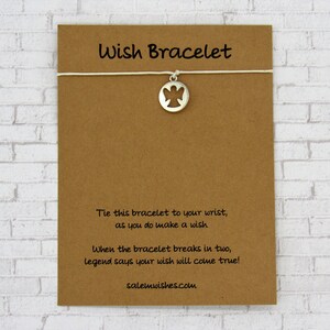 May include: A brown card with the text "Wish Bracelet" printed on it. The card has instructions on how to make a wish with the bracelet. The bracelet has a silver charm with an angel cutout.