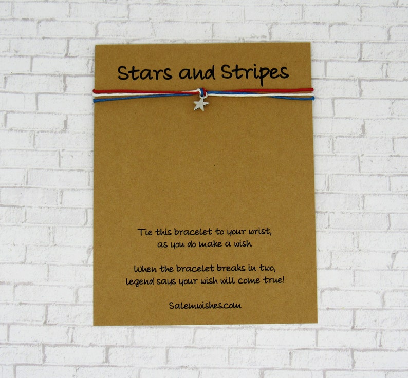 K&ouml;nnte beinhalten: Eine braune Karte mit dem Text "Stars and Stripes" darauf gedruckt. Die Karte enth&auml;lt auch Anweisungen f&uuml;r ein Gl&uuml;cksarmband: "Binde dieses Armband an dein Handgelenk, w&auml;hrend du dir etwas w&uuml;nschst. Wenn das Armband in zwei Teile zerbricht, besagt die Legende, dass dein Wunsch in Erf&uuml;llung geht!" Die Karte enth&auml;lt auch die Website-Adresse "Salemwishes.com".