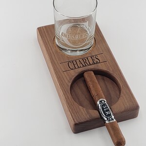 Peut inclure: Un plateau en bois avec un verre et un cigare reposant dans leurs emplacements d&eacute;sign&eacute;s. Le plateau est grav&eacute; du nom "CHARLES" et le verre porte la m&ecirc;me inscription grav&eacute;e.