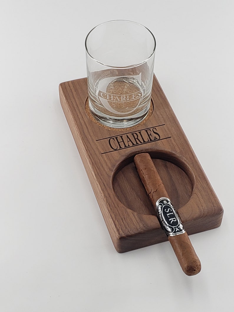 Peut inclure: Un plateau en bois avec un verre et un cigare reposant dans leurs emplacements d&eacute;sign&eacute;s. Le plateau est grav&eacute; du nom "CHARLES" et le verre porte la m&ecirc;me inscription grav&eacute;e.