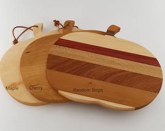 May include: Three round wooden cutting boards, one made of maple, one of cherry, and one with random wood strips. The boards have leather handles.