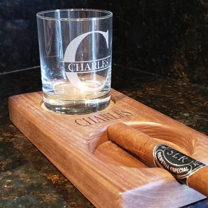 Peut inclure: Un plateau en bois avec un verre et un cigare reposant dans leurs emplacements d&eacute;sign&eacute;s. Le verre est grav&eacute; de la lettre "C" et du nom "Charles". Le cigare est de la marque "SRC Reserva Especial".