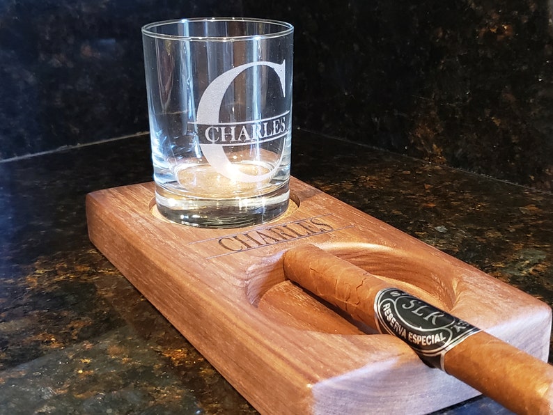Peut inclure: Un plateau en bois avec un verre et un cigare reposant dans leurs emplacements d&eacute;sign&eacute;s. Le verre est grav&eacute; de la lettre "C" et du nom "Charles". Le cigare est de la marque "SRC Reserva Especial".