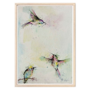 Könnte beinhalten: Ein Aquarellbild von drei bunten Kolibris im Flug vor einem hellbeigen Hintergrund mit Farbspritzern. Die Kolibris sind in Grün-, Blau-, Rosa- und Gelbtönen gemalt.