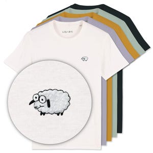 K&ouml;nnte beinhalten: Eine Auswahl an kurz&auml;rmeligen T-Shirts in verschiedenen Farben, darunter Wei&szlig;, Gr&uuml;n und Gelb. Das wei&szlig;e Shirt hat ein kleines gesticktes Schafmotiv und den Markennamen "LIGARTI" auf dem Kragen. Eine Nahaufnahme zeigt das Schafdesign.